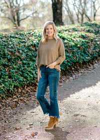 Blonde model wearing olive sweater with jeans and booties. 