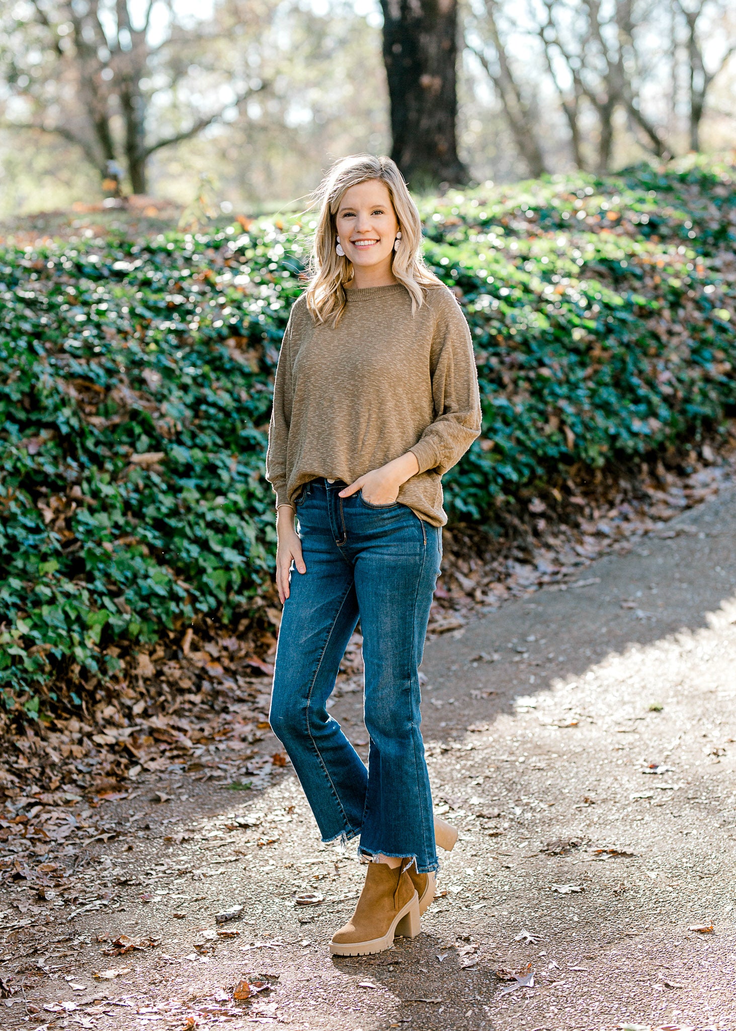 Blonde model wearing olive sweater with jeans and booties. 