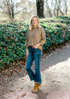 Blonde model wearing olive sweater with jeans and booties. 