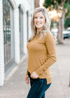 Blonde model wearing dark khaki long sleeve top.