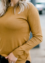 Close up of Blonde model wearing dark khaki long sleeve top.