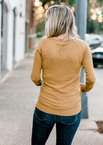 Back view of Blonde model wearing dark khaki long sleeve top.