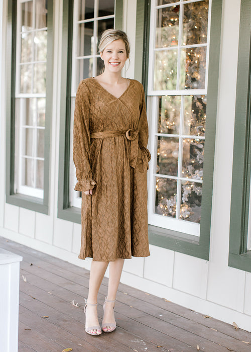 Blonde model in textured warm brown faux wrap dress and heels