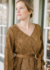 NEck detail of Blonde model in textured warm brown faux wrap dress.