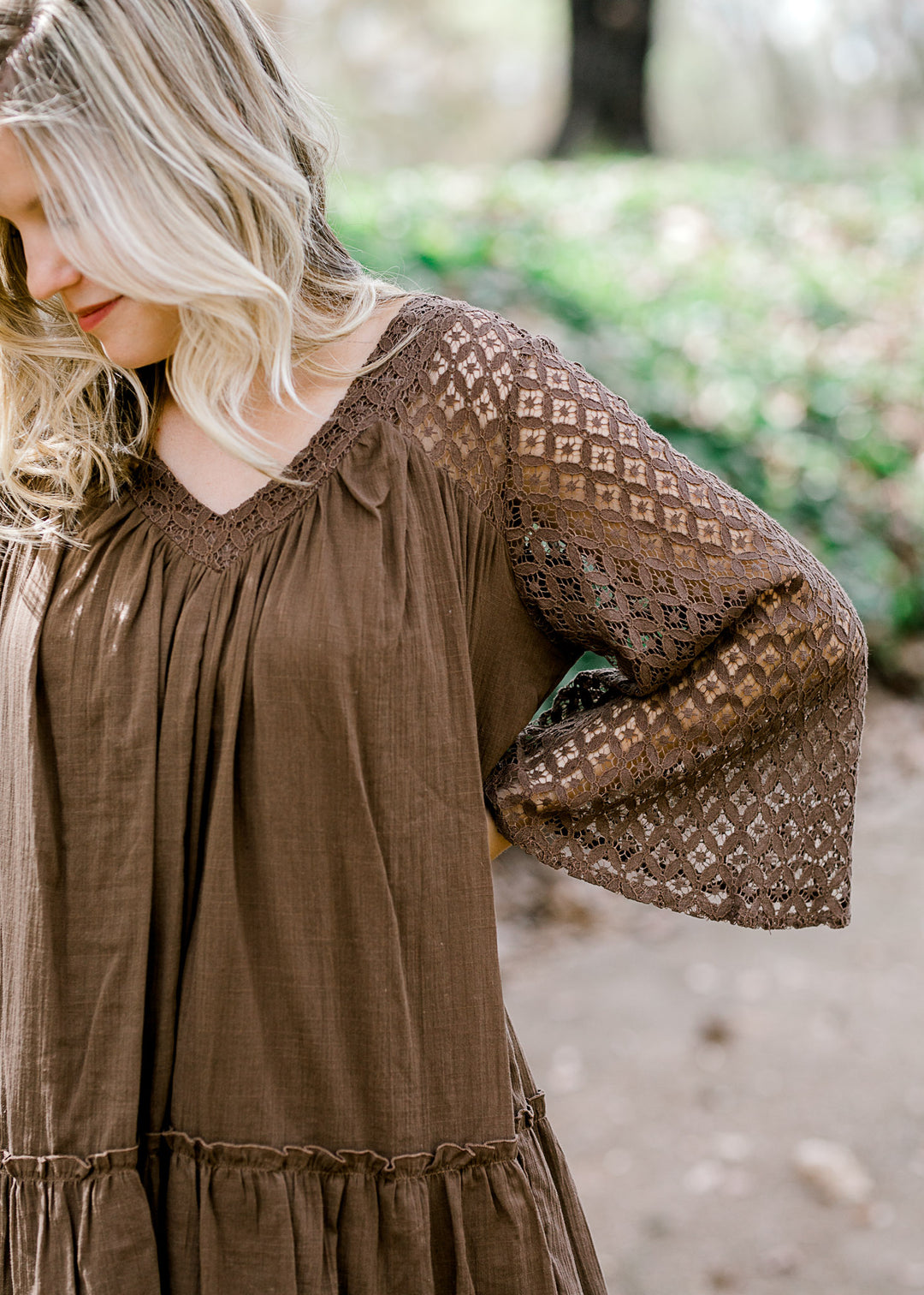 Blonde model wearing mocha colored top with lace sleeves.