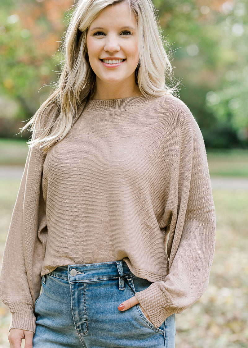 Blonde model wearing camel sweater. 