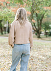 Back view of Blonde model wearing camel sweater. 