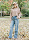 Blonde model wearing camel sweater with jeans and booties.