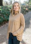 Blonde model wearing a taupe long sleeve top. 