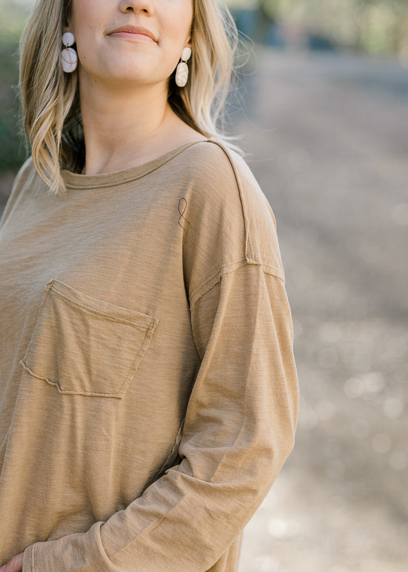 Close up view of pocket on taupe long sleeve top. 