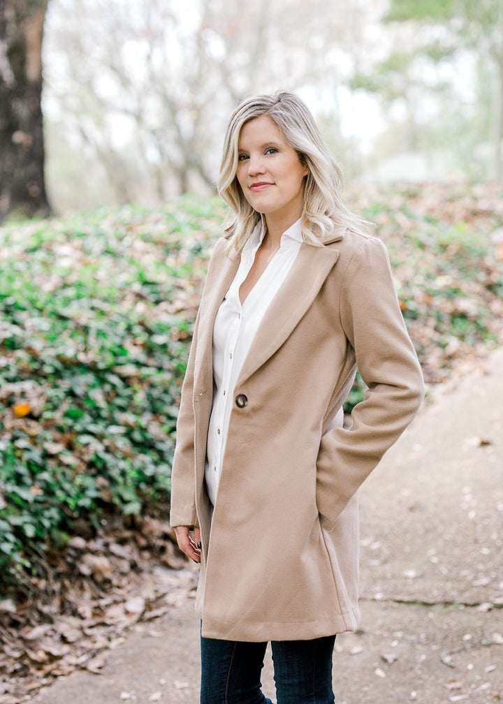 Blonde model wearing camel color coat. 