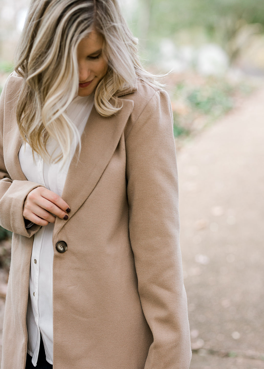 View of single button closure on camel colored coat.