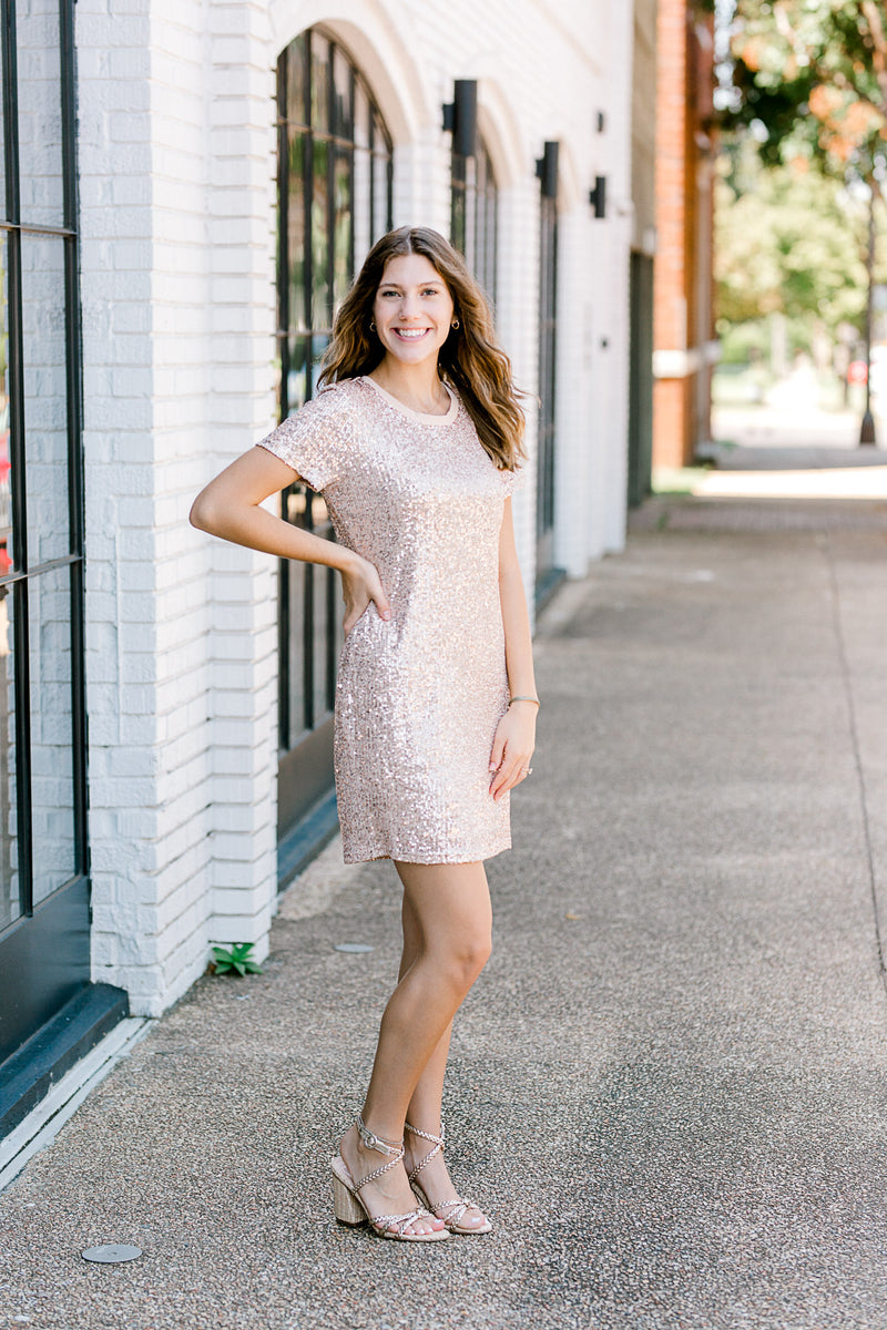 Brunette model with hand on hip, wearing short sleeve sequin dress with heels.
