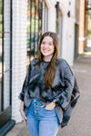 Brunette model wearing mottled charcoal sweater with jeans.