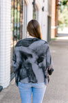 Back view of Brunette model wearing mottled charcoal sweater.