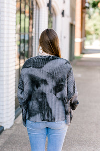 Back view of Brunette model wearing mottled charcoal sweater.