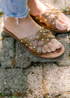 Close up of Model wearing brown studded faux leather sandals. 