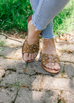 Model wearing brown studded faux leather sandals. 