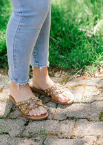 Side view of Model wearing brown studded faux leather sandals. 