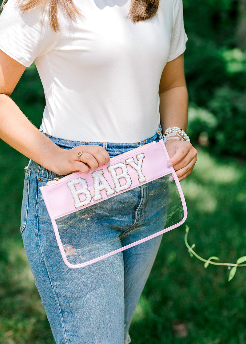 Blonde model holding clear pouch with baby written in varsity letters.  