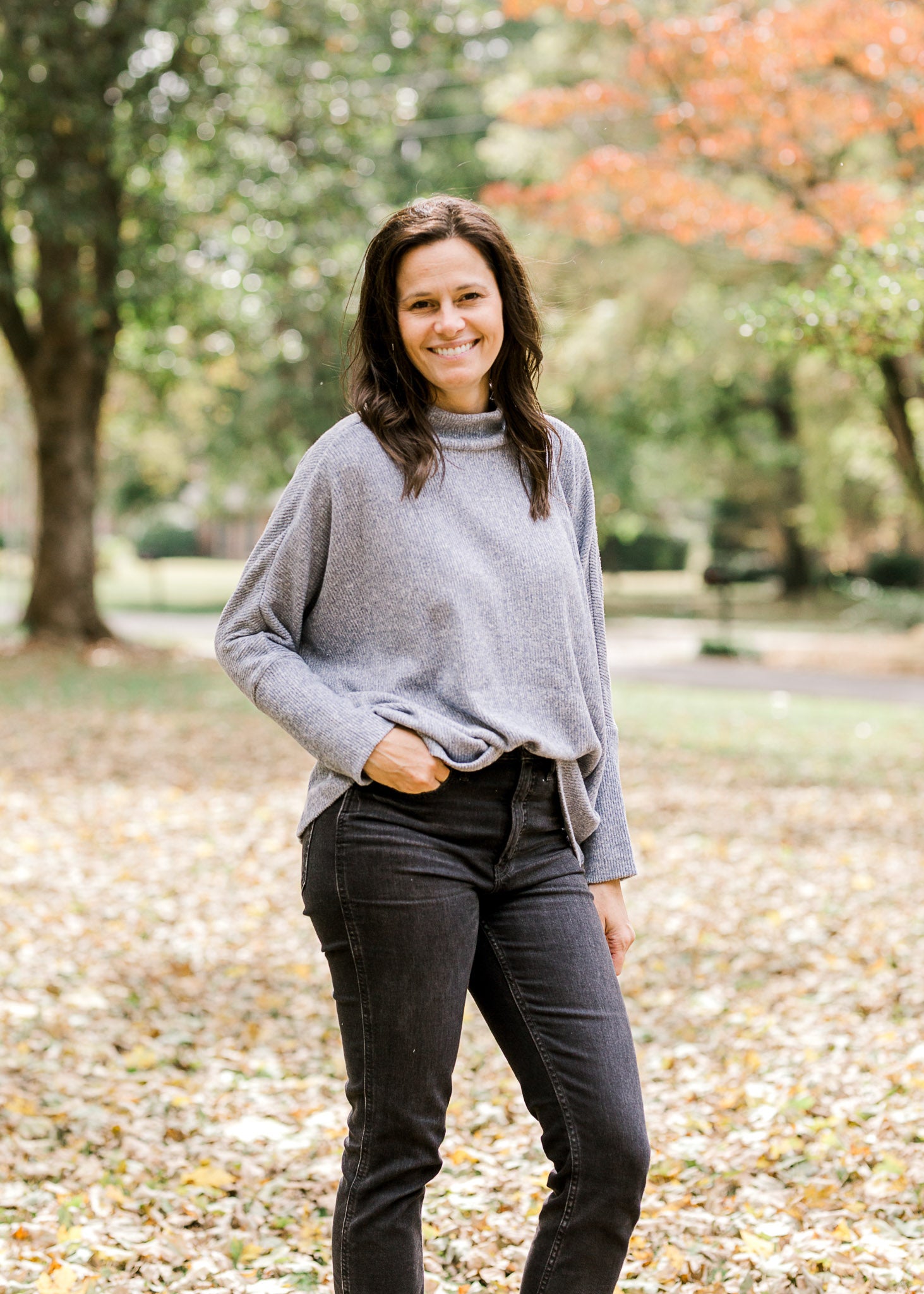 Brunette model wearing light blue sweater with black jeans.