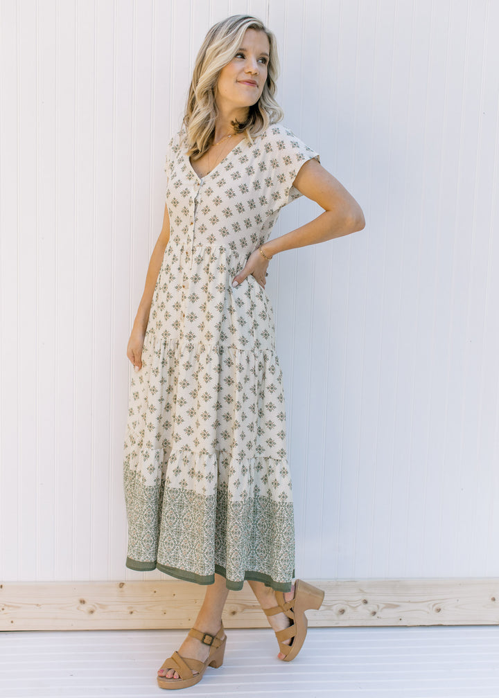 Model wearing a cream, button down midi dress with hunter green pattern and short sleeves. 