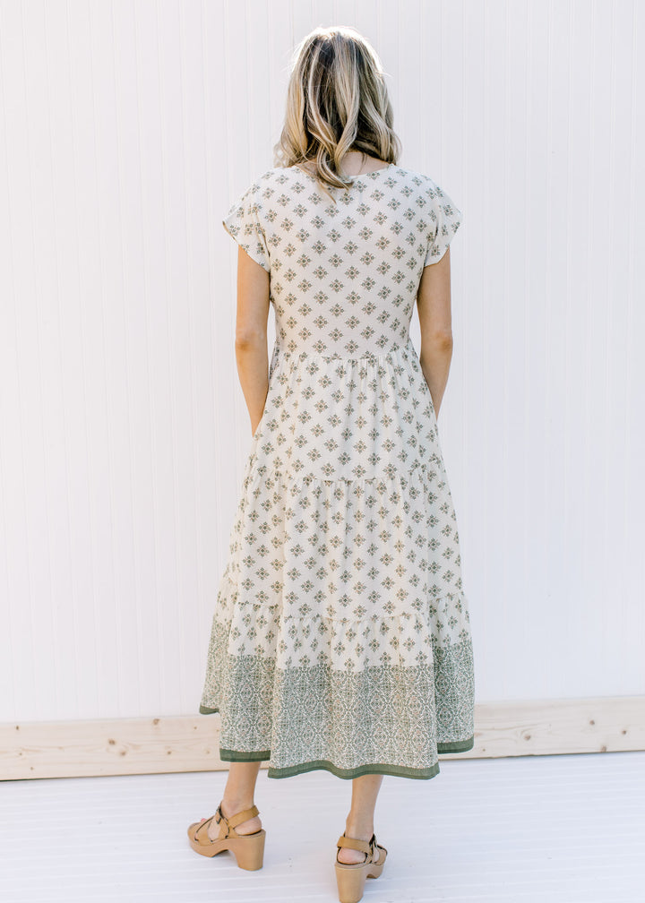 Back view of Model wearing a cream, button down midi dress with hunter green pattern. 