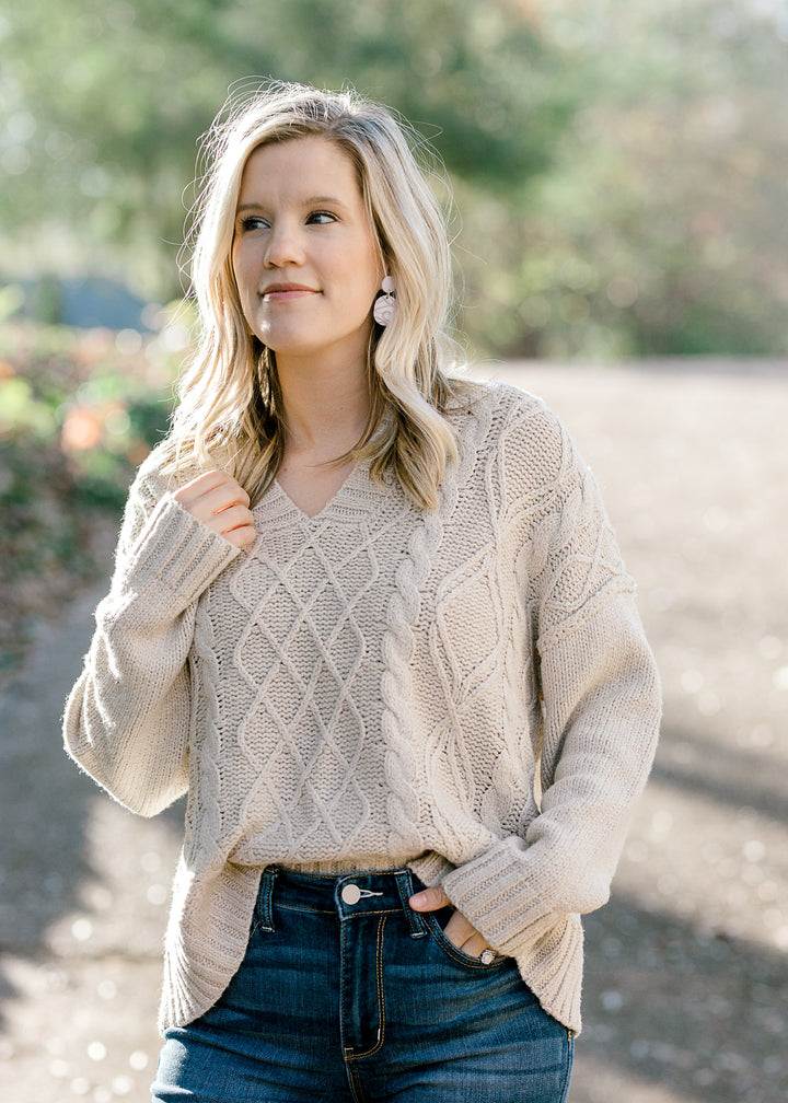 Blonde model wearing cream cable knit sweater.