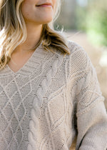 Close up view of v-neck on cable knit sweater.