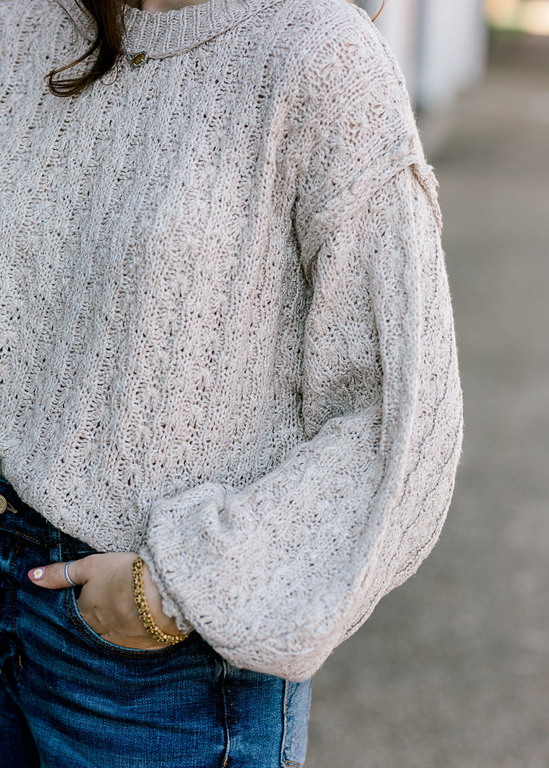 Close up view of bubble sleeve on gray cable knit sweater.