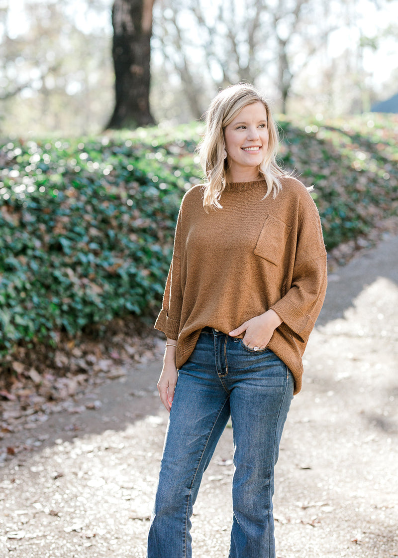 Blonde model wearing copper colored sweater. 