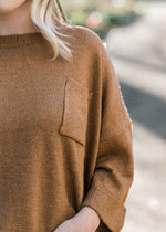 Close up view of pocket on copper colored sweater. 