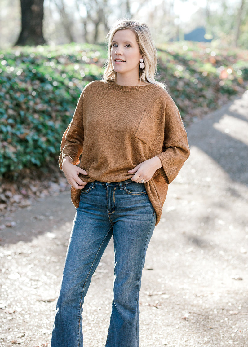 Blonde model wearing copper colored sweater with jeans. 