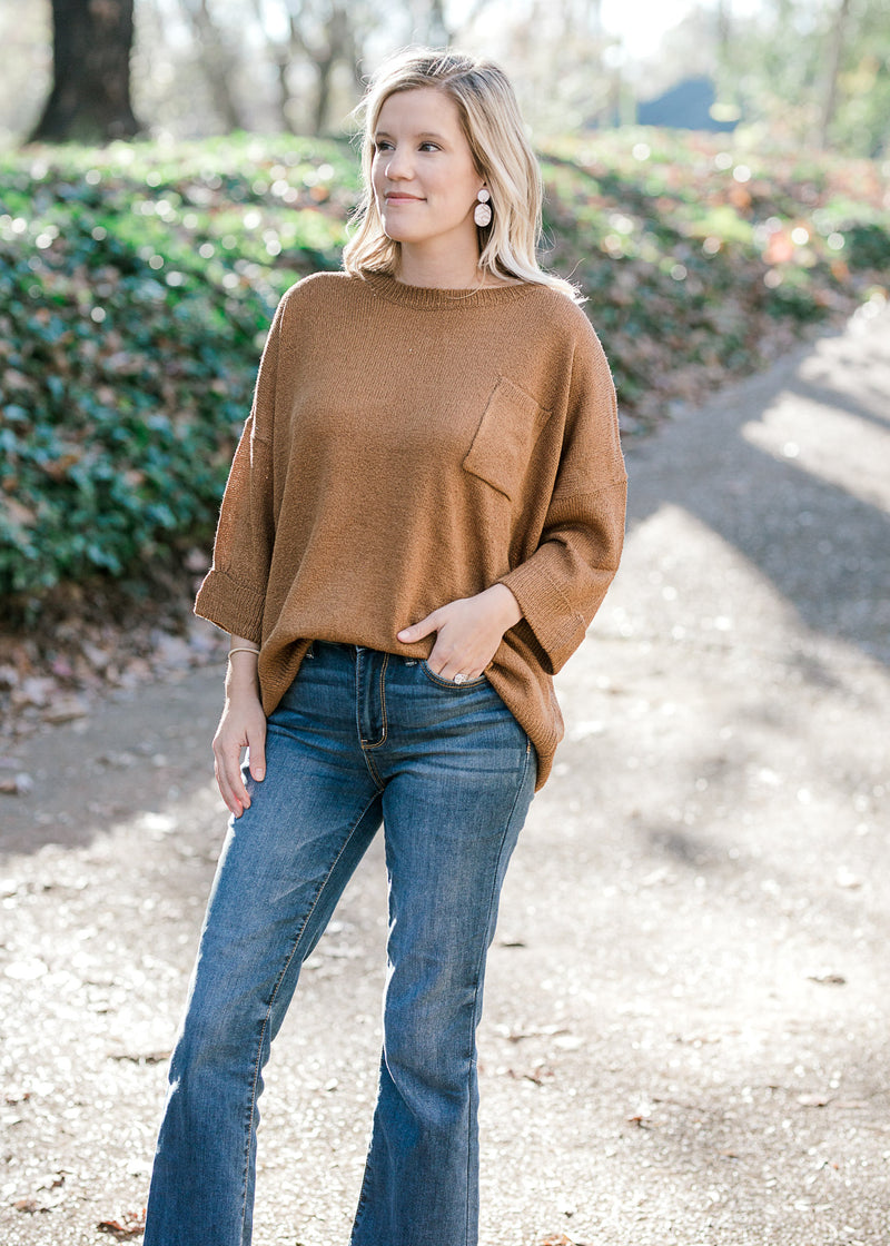 Blonde model wearing copper colored sweater with pocket detail and 3/4 sleeves. 
