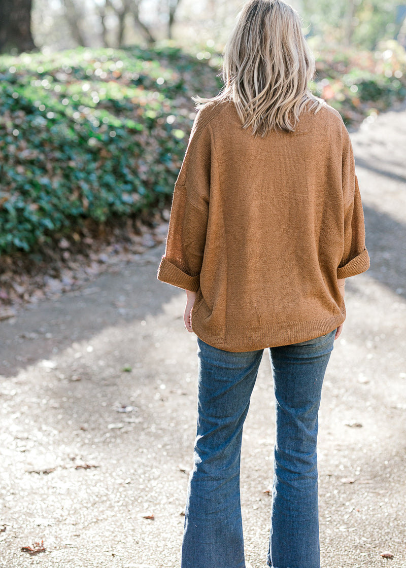 Back view of Blonde model wearing copper colored sweater. 
