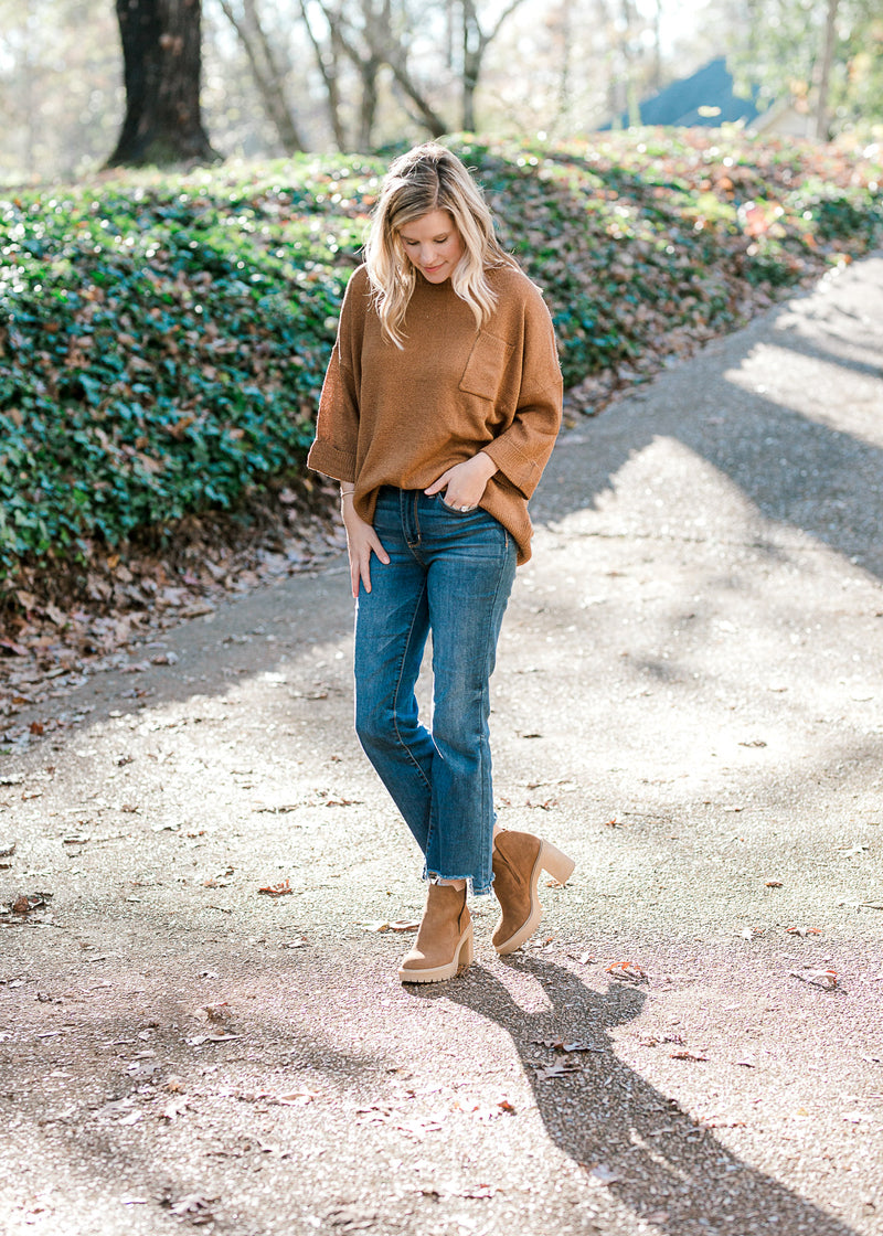Blonde model wearing copper colored sweater with jeans and booties. 