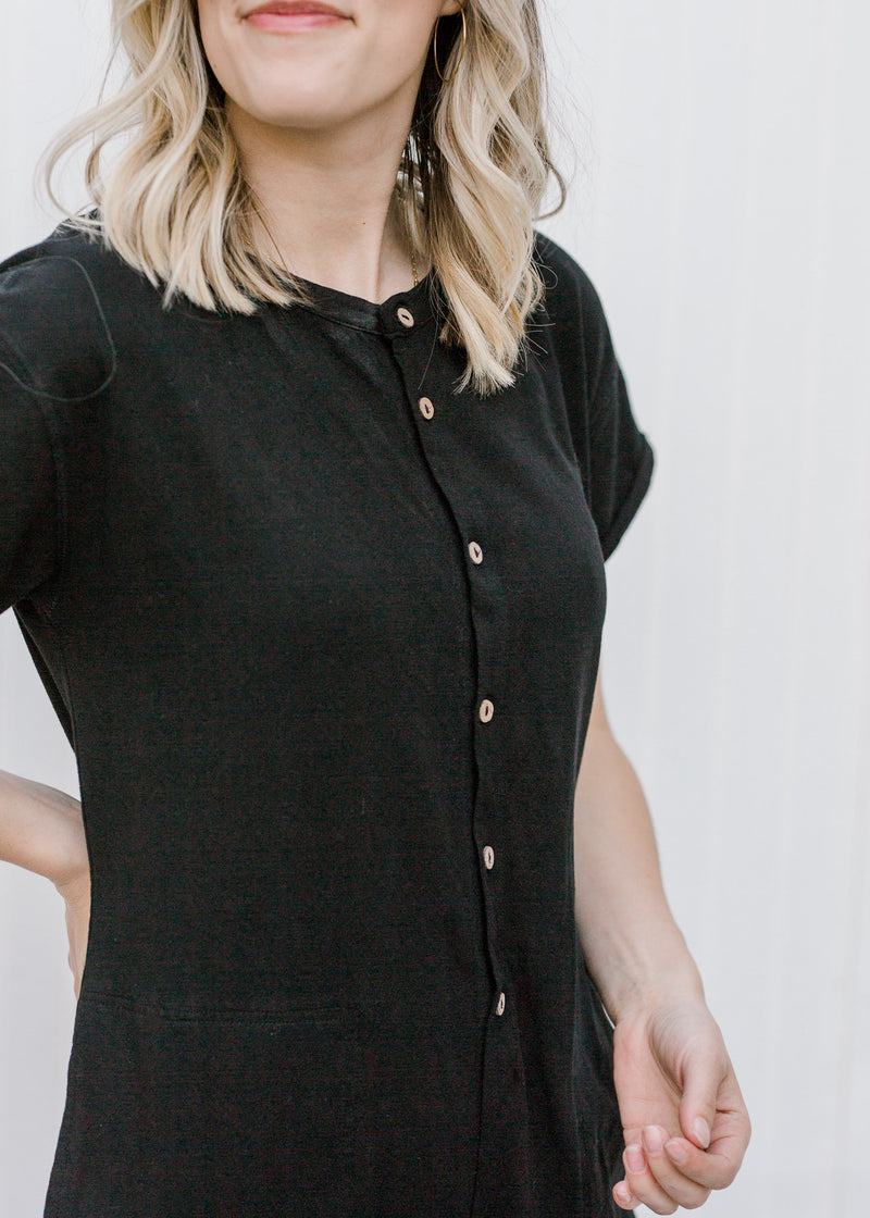 Close up of buttons on Blonde model wearing a black jumpsuit.