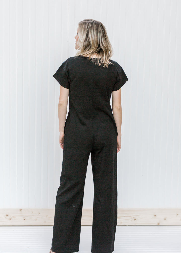 Back view of Blonde model wearing a black jumpsuit.
