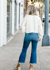 Back view of Blonde model wearing a cream cable knit sweater.