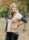 Blonde model wearing cream, camel, gray and brown color block sweater. 
