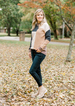 Blonde model wearing cream, camel, gray and brown color block sweater with jeans and booties.