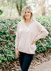 Blonde model wearing a cream v-neck sweater. 
