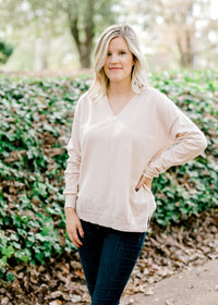 Blonde model wearing a cream v-neck sweater. 