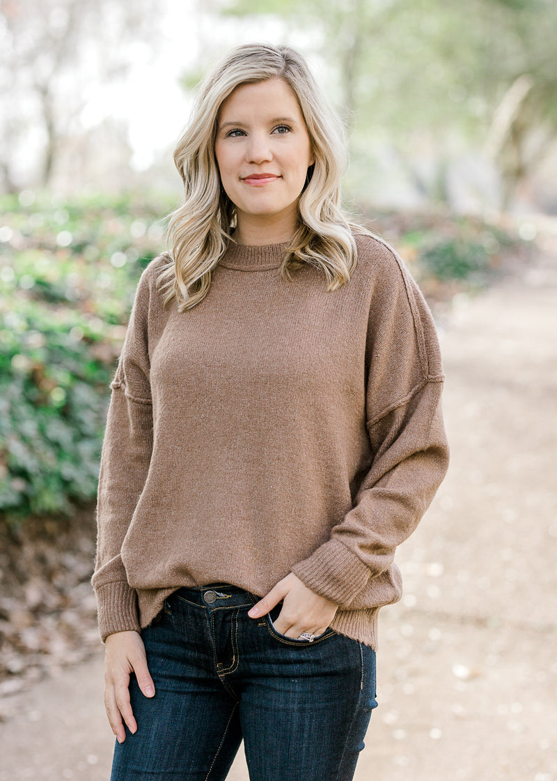 Blonde model wearing light brown sweater. 