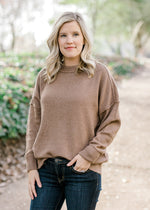 Blonde model wearing light brown sweater. 