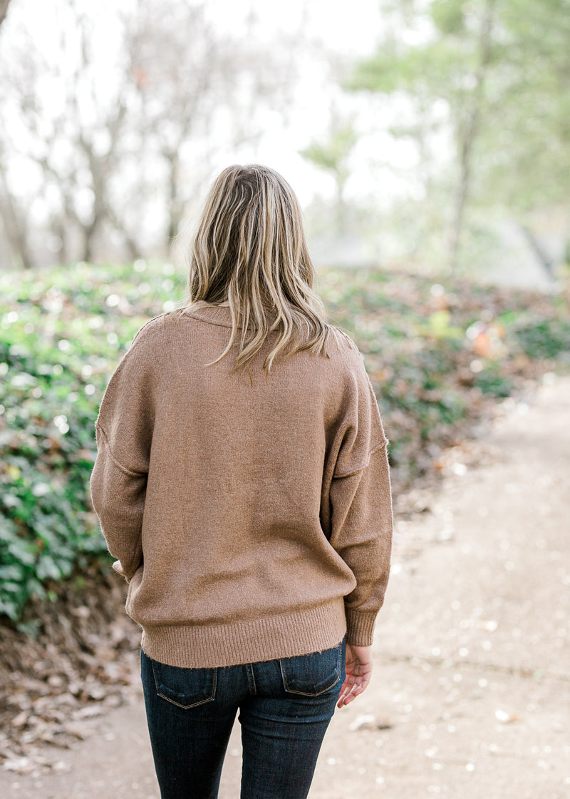 Back view of Blonde model wearing light brown sweater. 