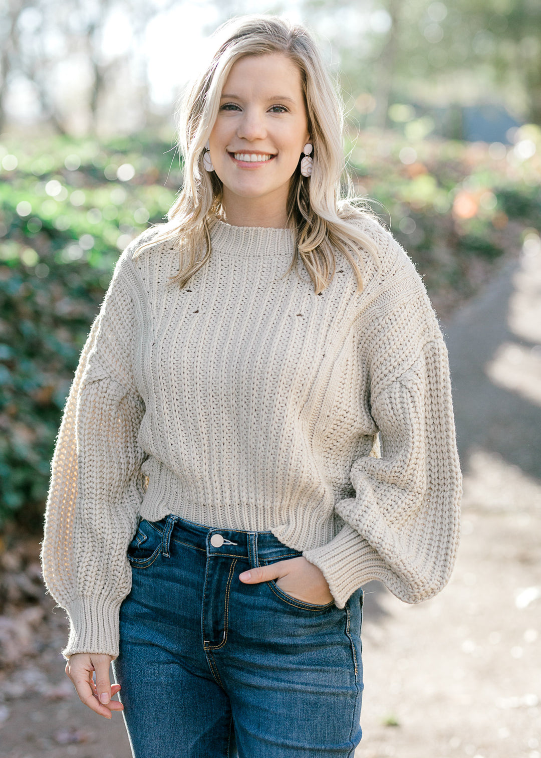 Blonde model warning a cream sweater with bubble long sleeves. 