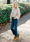 Blonde model wearing cream sweater with jeans and booties. 