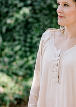 Details of Blonde model wearing cream top with military details and mixed fabrics.