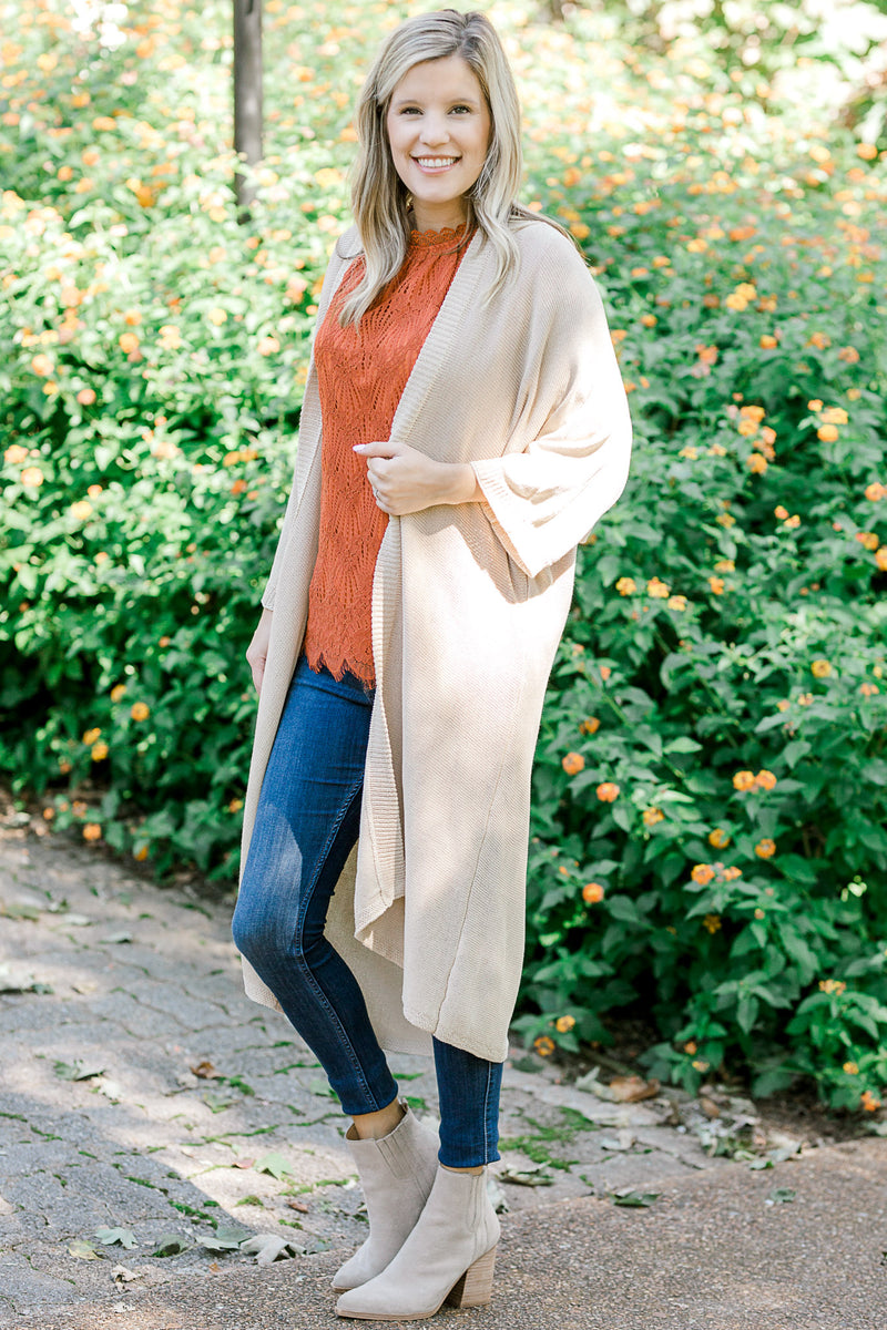 Blonde model wearing cream duster cardigan with coral top.